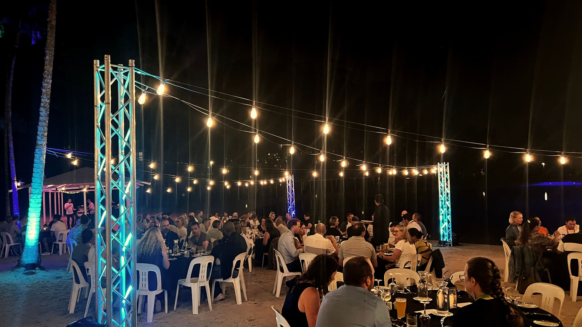 Festoon lighting strung over a corporate beach dinner at night — installed by Lume Hire